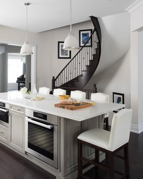 Taupe center kitchen island with an oven and microwave topped with a white quartz counter slab under a set of frosted and chrome pendant lights. Island With Oven, Kitchen Island With Cooktop, Circular Staircase, Island With Stove, Kitchen Island With Stove, Custom Island, Taupe Kitchen, Kitchen Island With Sink, Kitchen Island Cabinets