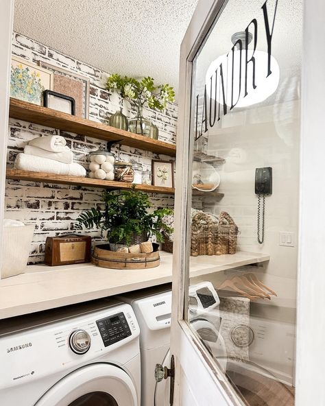 Farmhouse laundry with open shelving and faux brick paneling touches of vintage decor and layers fresh spring florals Faux Brick Laundry Room, Brick Wallpaper In Laundry Room, Exposed Brick Laundry Room, Fake Brick Wall Laundry Room, Laundry Room With Faux Brick Wall, Cottage Laundry Room, Farmhouse Laundry, Laundry Room Shelves, Farmhouse Laundry Room