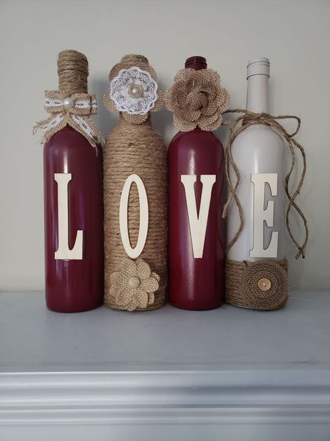 This set is painted cranberry and smokey beige. I used jute cord for one bottle and burlap flowers for embellishment. I can also customize orders (such as first or last name). Price listed is for 4 bottles if needing more the price will be $8 extra for each additional bottle. Message me if interested. These sets make great Birthday gifts, wedding gifts, shower gifts, etc... bottle sizes can vary slightly in height and weight. Flower sizes can also vary in shape and size. Diy Wine Bottle Decor For Wedding, Decorating Wine Bottles With Flowers, Decorated Wine Bottles For Wedding, Wedding Bottle Decorations, Wine Bottle Centerpieces For Wedding, Wine Bottle Crafts With Jute, Black Wine Bottle Decor, Jar Decorations, Clothespin Art