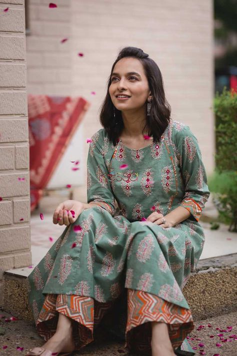 This exquisite set comes with an A-line kurta with ethnic handblock pattern and yoke adorned with multi color piping. The handblock pattern in yoke is decorated with embroidery and mirror work, along with a button enclosure on the neckline. The pants features a vibrant chevron pattern in hues of red, orange, yellow and paradise green. Simple Kurti, Chevron Pants, Cotton Kurtis, Salwar Pattern, Suit Ideas, Kurti Patterns, Simple Kurti Designs, Kurti Neck, Kurti Embroidery Design