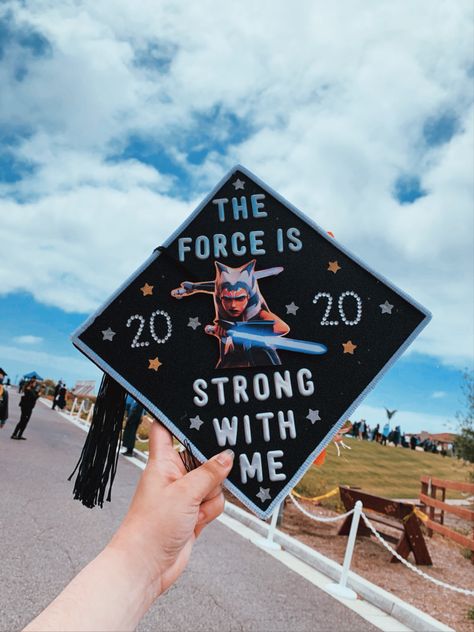 A blue sky with clouds and a hand holding a graduation cap decorated with Ahsoka Tano in the middle. Words around Ahsoka read “The force is strong with me.” Ahsoka Graduation Cap, Starwars Graduation Caps, Graduation Cap Star Wars, Star Wars Graduation Cap Ideas, Httyd Graduation Cap, Graduation Cap Designs Star Wars, Star Wars Graduation Cap, Graduation Cap Diy, Disney Graduation Cap