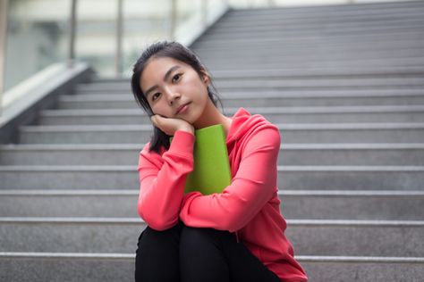 A young person sits on a staircase, one arm wrapped around a green book, the other supporting their head which rests in their hand. Person Resting Head On Hand, Resting Head On Hand, Head On Hand, Feminist Pins, Green Book, Black Dating, Indian People, Meet Guys, Flirting Quotes For Her