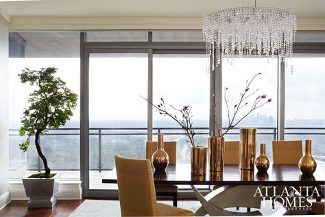 A sculptural table by Henry Royer serves as the dining room’s centerpiece. Rudin dining chairs featuring a textured Robert Allen fabric complement the table’s clean lines. The prism chandelier by Schonbek Lighting was hung closer to the ceiling to showcase views of the Buckhead skyline. Penthouse Decor, Taupe Color Schemes, Atlanta Homes And Lifestyles, Penthouse Living, Sculptural Table, Schonbek Lighting, Steel Table Base, Robert Allen Fabric, Atlanta Homes