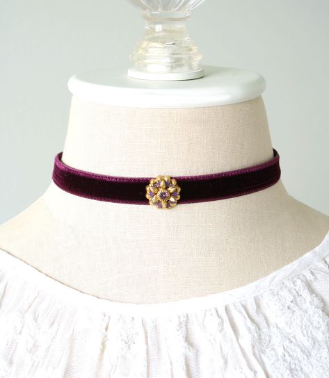 This eye-catching choker necklace is handmade with a soft rayon velvet ribbon in a deep burgundy (eggplant) purple hue. It features a vintage sparkling Swarovski crystal amethyst jewel in a beautiful gold tone setting. A one-of-a-kind gift for a friend who loves unique jewelry! Also available with blue velvet ribbon. See last group photo showing coordinating necklaces... listed separately in the Rosy Posy Designs shop. * Size ~ Adjustable length 12 - 15 inches with extender chain Please check yo Purple And Gold Jewelry, Circus Accessories, Cowgirl Oc, Amethyst Necklace Vintage, Choker Velvet, Rosy Posy, Blue Velvet Ribbon, Purple Choker, Poster Business