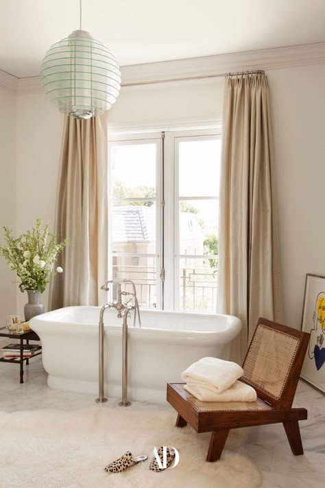 A Gio Ponti pendant light hangs above a Waterworks tub and a Pierre Jeanneret folding chair in Ellis’s primary bathroom. The whole space feels very European-inspired as if you could open the windows to a view of the Eiffel Tower. Muted tans and neutrals are used throughout the room and offer a very zen and calming vibe, all while decor elements create a very chic and elegant bath. #bathroom #guestbath #tub #bathtub #selfcare #skincare #spa #skinroutine #athomespa #curatins #chair #towels #lights William Hefner, Bathroom Chair, Pierre Jeanneret, Contemporary Dining Room, Luxury Homes Interior, Gio Ponti, Timeless Luxury, Modern Dining Table, Lifestyle Magazine