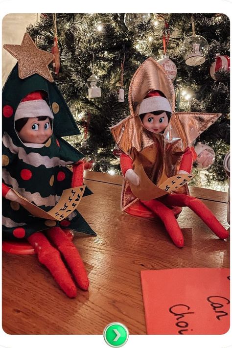 Two elves sitting together in Christmas caroling outfits. This cute Elf on the Shelf idea brings holiday cheer with an easy caroling setup in front of the Christmas tree. Elf On Shelf Tree Ideas, Elf On The Shelf Christmas Caroling Ideas, Christmas Caroling Outfits, Elf On The Shelf Outfits, Elf On The Shelf Idea, Christmas Caroling, Sitting Together, Elf On The Shelf Ideas, Shelf Ideas