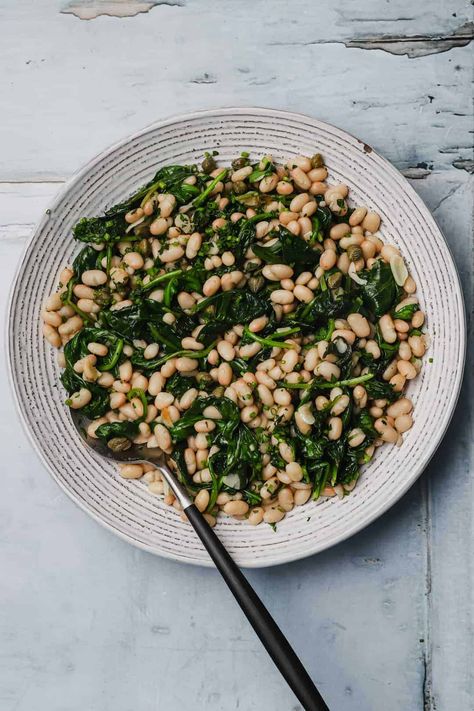 Garlic spinach with white beans is a healthy and nutritious side dish that pairs well with any number of entrées, from rotisserie chicken to seared salmon. Sautéed spinach is seasoned with garlic and small canned white beans, then flavored with fresh lemon juice and finely chopped herbs and capers. A vegetable side that is filling and flavorful! Whole30, V #wellseasonedstudio #garlicspinach #sautéedspinach #whitebeans #garlic #spinach White Bean Recipes, Garlic Spinach, Seared Salmon, Sauteed Spinach, Great Northern Beans, Baked Salmon Recipes, Vegetarian Lunch, Vegetable Side, Green Bean Recipes