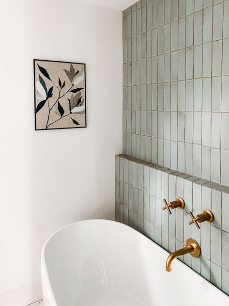 Looking for a modern, earthy bathroom design that will make you feel like you're at the spa? In this client design project, Dwell October used hand-glazed green brick tile to create a backdrop for a free-standing soaking tub. A wall-mounted brass faucet adds an elegant touch. Read on for sources and more details. Vertical Tile Behind Vanity, Backsplash Behind Freestanding Tub, Small Wet Room Bathroom With Tub, Ledge Behind Tub, Tile Behind Tub, Modern Earthy Bathroom, Free Standing Tub Ideas, Bathroom 2024 Design Trends, Wet Room Bathroom With Tub