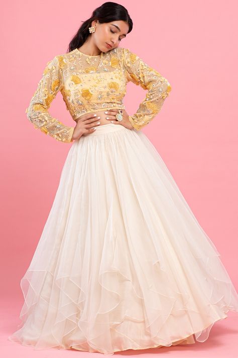 Featuring a pastel yellow crop top in organza base with 3D embellishments. It is paired with a contrasting ivory asymmetrical layered lehenga and a bustier in chanderi base.  FIT: Fitted at bust and waist. COMPOSITION: Organza, Chanderi. CARE: Dry clean only. Crop Top And Lehenga, Top And Lehenga, Ethnic Lehenga, Full Sleeve Crop Top, Layered Lehenga, Ruffled Saree, Organza Cape, Floral Embroidered Shirt, Lehenga Crop Top