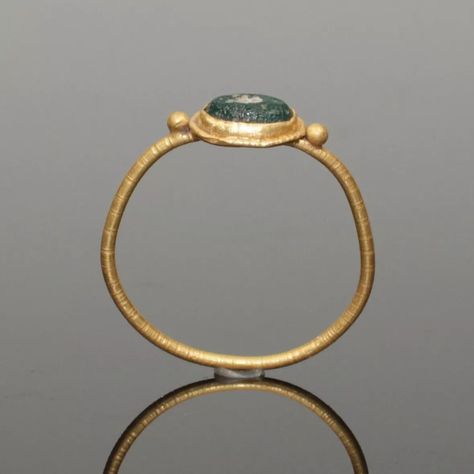 LOVELY ANCIENT ROMAN GOLD RING. ANCIENT ROMAN GOLD RING. DATES: CIRCA 2nd CENTURY AD. SUPPORTING A CENTRAL OVAL BEZEL SET WITH AN IRIDESCENT GREEN GLASS STONE. HAVING A SOLID BAND..#jewelrylover #handcraftedjewelry #jewelryinspiration #jewelrydesign #jewelryobsessed #jewelryoftheday #jewelrygoals #jewelryfashion #jewelrytrends Sun Outfits, Ancient Gold Ring, Roman Jewellery, Black Nativity, Storm Comic, Ancient Rings, Lost Wax Jewelry, Etruscan Jewelry, Medieval Ring