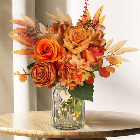 PRICES MAY VARY. Fall Artificial Flowers in Vase - This fall faux flowers in vase set features elegant orange roses, dahlia, fall hydrangea artificial flowers, lifelike eucalyptus stems, and a glass vase with heart pendants and LED copper lights. Simply arrange the fall fake flowers into the vase and enjoy fall decor centerpiece for your dining table or coffee shop. Realistic Look and Beautiful - With a realistic look, this fall artificial flower in the vase will add a touch of beauty to your ho Fall Theme Floral Arrangements, Sunflower Fall Centerpieces, Fall Theme Table Decor, Fall Wedding Table Centerpieces Flowers, Fall Fake Flower Arrangements, Fall Office Decor Work, Faux Flowers In Vase, Thanksgiving Flower Arrangements, Fall Flower Centerpieces