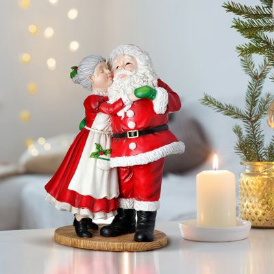 All the presents are ready and the clauses are ready to enjoy the holidays. Bring this adorable 12" Mrs. Claus kissing Santa home this Christmas. Crafted of resin in red, green, and white hues. Place on end tables, nightstands, and mantels. Display in windows and decorate your kitchen. Intended for decorative use only. Wipes clean with a damp cloth. Overall dimensions are 12" H x 6" W x 9" L 3lbs. Mrs Claus Figurines, Christmas Competitions, Realistic Artificial Christmas Trees, Storing Christmas Decorations, Christmas Nutcrackers, Christmas Tabletop, Santa Figurines, Fun Christmas Decorations, Christmas Central