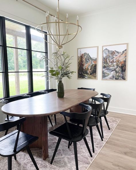 Stained wood oval dining table is lit by a gold chandelier in this dining room with black frame windows. Black wishbone chairs are seated around the table on a white and light purple rug. Dining Table Decoration Ideas, White Oval Dining Table, Dark Wood Dining Room, Wood Oval Dining Table, Oval Wood Dining Table, Eagle Landing, Oval Dining Room Table, Dark Wood Dining Table, Living Room Decoration Ideas