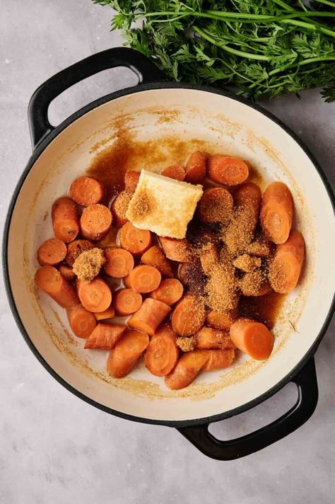 A skillet filled with sliced carrots, butter, and brown sugar, ready to be cooked into delicious Honey Glazed Carrots. Fresh carrot tops are seen in the background. Honey Ginger Glazed Carrots, Stovetop Honey Glazed Carrots, Slow Cooker Honey Glazed Carrots, Honey Dill Carrots, Cooked Carrots With Brown Sugar, Baked Honey Glazed Carrots, Honey Glazed Carrots Oven, Glaze Carrots, Cracker Barrel Carrots