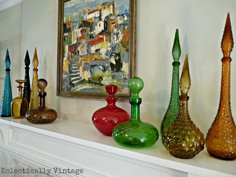 Vintage glass decanter collection on   the mantle Glass Collection Display Ideas, Displaying Art Glass, Colored Glass Decor, Decanter Decor Ideas, Vintage Bottle Display, Glass Collection Display, Vintage Decanter Display, Display Fireplace, Vintage Glass Display