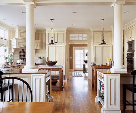 This kitchen is right in the middle of the home's main traffic flow. To keep passersby out of the way, the owners divided the kitchen with two islands and left ample room for a walkway in the center. This layout creates dedicated work zones on each side of the kitchen. Peninsulas that support the Colonial-style columns offer seating where friends and family can gather outside the kitchen but still chat with the cook. Kitchen Island With Columns, Kitchens With Two Islands, Kitchen Divider, Small Open Kitchens, Open Kitchen Layouts, Open Floor Plan Kitchen, Large Open Kitchens, Kitchen Conversion, Loft Kitchen