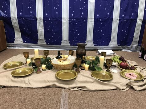 This is a table set up for the Last Supper lesson for first graders. We also talked about Passover and sampled other Biblical foods.   Edible items:  Grape juice Naan (for unleavened bread) Pomegranate Grapes Pitted kalamata olives  Dates Goat cheese crumbles  Almonds Plain Greek yogurt Roast beef (for lamb)  Decorative items: Fish (realistic play food) Olive oil Balsamic vinegar  Honey (in a jar w/ comb) Seder plate Small satchel with 30 coins The Last Supper Table Setting, The Last Supper Decor Ideas, Passover Flower Arrangements, Last Supper Decor Ideas, Last Supper Table Decoration, Dates Goat Cheese, Bethlehem Dinner, Goat Cheese Crumbles, Realistic Play Food