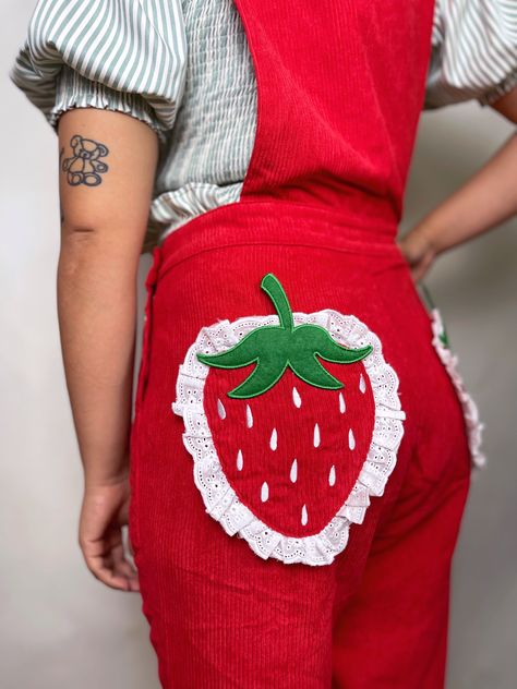 Step into adventure with our vibrant red Strawberry Overalls, adorned with a bold embroidered strawberry and delicate lace trim, perfectly complemented by matching back pockets. These overalls are your ultimate companion for carefree skipping through fields of grass, where every step is a joyful stride. As you explore, keep an eye out for a dandelion awaiting your wish—it's a treasure hunt of whimsy and delight! Details: Corduroy Embroidered face Side pockets and bib pocket Model is wearing size Strawberry Overalls, Wacky Outfits, Embroidered Strawberry, Clothing Making, Art Outfit, A Dandelion, Strawberry Dress, Embroidered Face, Quirky Fashion