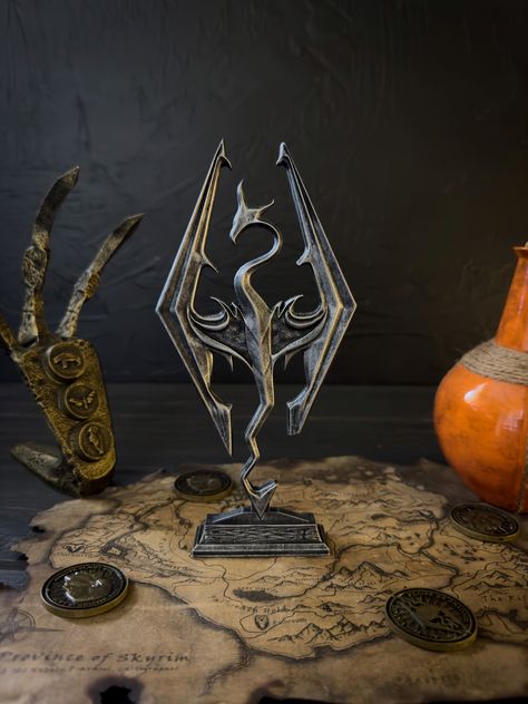 This figurine is the emblem of the RPG Skyrim, the logo of the video game called the Seal of Akatosh. It not only looks cool, but symbolizes power, patronage, and protection. The item is perfect for gifts and decorations! If you are a Skyrim fan, it`s a must-own. The logo is on a stand, so you can use the figurine to decorate your house or office! This sculpture was made of high-quality resin. The item was hand painted with acrylic paint. Then we finished it with varnish. It is handmade and hand Skyrim Room Decor, Skyrim Statue, Skyrim Decor, Dragon Skyrim, Nerdy Decor, Diy Laser Engraver, Skyrim Dragon, Dungeon Room, Nerd Decor