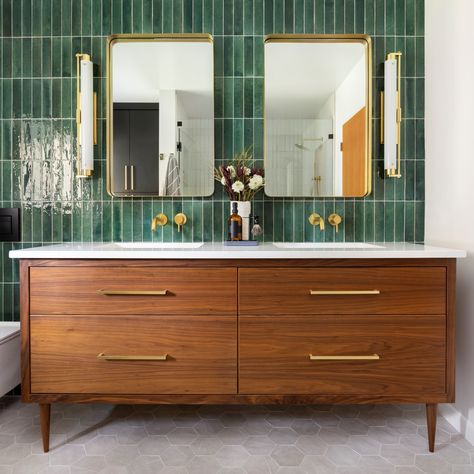 GRAFF’s Brushed 24 Karat Gold designs pop against dazzling emerald green subway tiles, and the warmth of a Mid Century Modern styled vanity give this space a trendy, sophisticated, and fun flare. Interior Design: Amy Pearson Design Photography: Meagan Larsen #interiordesign #modernbathroom #luxuryhomes #bathroominspiration #luxurybathroom #GRAFFDesigns #ArtofBath #AmyPearsonDesign #MeaganLarsenPhotography #Midcenturymodern #subwaytiles #24KGold Green Accent Wall, Green Tile Bathroom, Green Accent Walls, Mid Century Modern Bathroom, Mid Century Bathroom, Apartment Decoration, Bad Inspiration, Transitional Bathroom, Upstairs Bathrooms