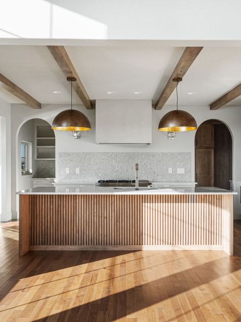 Wooden accents on kitchen islands add texture and color. We love this kitchen island combination with the wooden beams and brass pendent lights. One Sided Waterfall Island Kitchen, Kitchen Island Paneling Ideas, Wood Slat Kitchen Island, Wood Slat Kitchen, Wooden Island Kitchen, Kitchen Island End Panels, Kitchen Island Ends, Kitchen Island Panels, Waterfall Island Kitchen