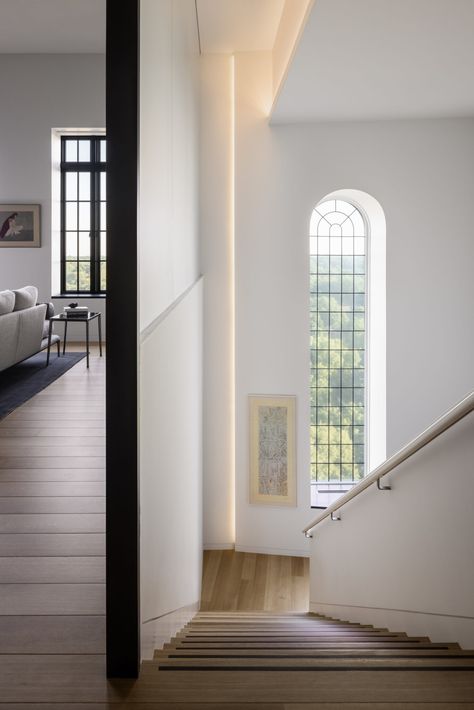 A translucent wall of frosted glass panels allows diffused natural light to be shared between the stairwell and the upper level. Here, the ceilings rise to over 14 feet and the spine, piercing through from the floor below.