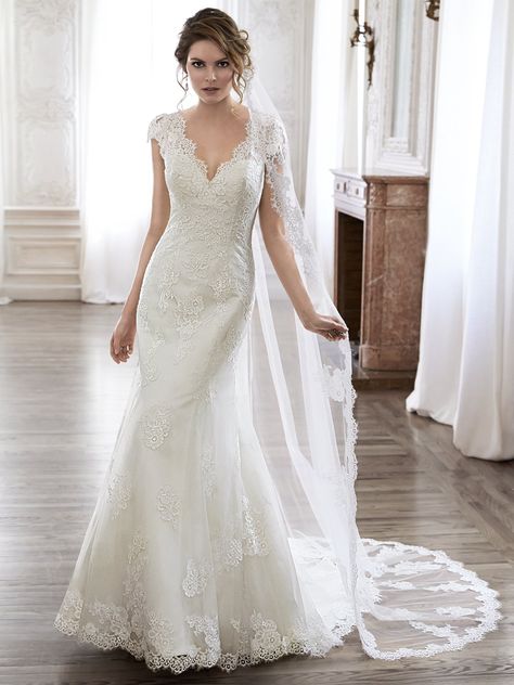 Maggie Sottero - PILAR, Completely timeless is this slim A-line wedding dress. Constructed of delicate lace and ethereal tulle, this gown features scalloped trim adorning the V-neckline and plunging back. Complete with dainty lace sleeves. Finished with covered button over zipper back closure.