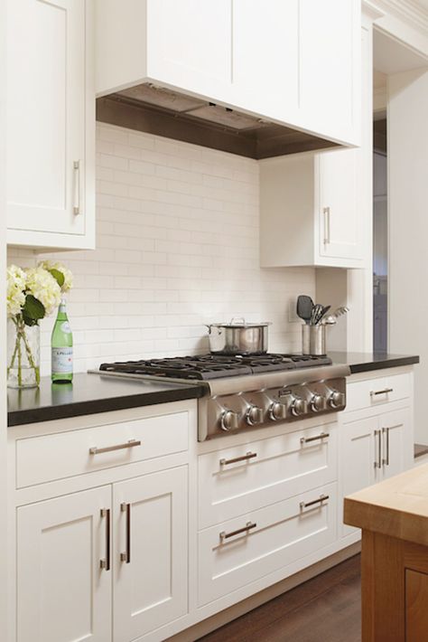 kitchen with white cabinets, brick pattern subway tile, built in vent fan, black counters, gas range Dove Kitchen Cabinets, White Dove Kitchen Cabinets, White Dove Kitchen, Inset Cabinetry, White Subway Tile Backsplash, Black Countertops, Mill Valley, Kitchen Hoods, White Dove