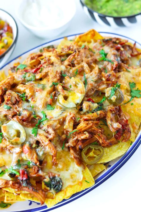 This Thai Basil Chicken Nachos is easy to make and the perfect fusion party appetizer for Thai food and nachos lovers! Spicy and garlicky Thai basil chicken, jalapeño peppers, and plenty of melty cheeses get piled high onto tortilla chips and baked to crispy, spicy, and cheesy fusion nachos perfection! #thainachos #thaibasilchicken #nachos #cincodemayo #fusionnachos #chickennachos #appetizer #gameday | That Spicy Chick Kra Pow, Thai Fusion Food, Jalapeño Peppers, Thai Basil Chicken, Juicy Baked Chicken, Chicke Recipes, Chicken Nachos, Basil Chicken, Thai Basil