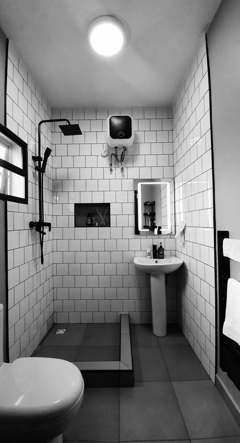 White tiles with black grout, mature black fittings and black towel rail. #Nigeria #Abuja #construction #renovation Toilet Black Tiles, Small Monochrome Bathroom, Black Tile Black Grout Bathroom, White Bathroom Tiles With Black Grout, Black Square Tile Bathroom, Bathroom White Tiles Black Grout, Old Bathroom Renovation, White Tiles Black Grout Bathroom, Industrial Toilet Design