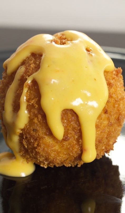 Close up of a golden brown fried ball of macaroni and cheese that is covered in cheese sauce. Mac And Cheese Balls Recipe, Mac Cheese Balls, Fried Mac And Cheese Balls, Fried Mac N Cheese Balls, Mac And Cheese Balls, Fried Macaroni And Cheese, Fried Macaroni, Cheese Balls Recipe, Mac N Cheese Balls