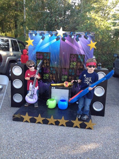 Rock Star Trunk or Treat setup Stage: Pallet & Chipboard, Stars(dollar tree) Backdrop: Scenesetter(Amazon) Speakers: cardboard boxes, spray paint  Instruments/microphones(Party City) Costumes:tees mad using vinyl cut on Cricut, glasses/bandana(Dollar Tree) All the kids had a blast taking turns being Rock Stars. It was very interactive! Dollar Tree Backdrop, Festa Rock Roll, Rock Star Theme, Pop Star Party, Tree Backdrop, Rockstar Party, Rock And Roll Birthday, Music Birthday Party, Rockstar Birthday