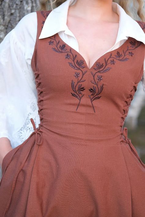 Along the bust and waistline are two fully adjustable side panels. The lacing can be taken in or out in order to give you a bit more room to cinch, move and change. The dress is adorned by delicate embroidery along the sweetheart neckline, inspired by the traditional national costumes of Norway. The dress features a midi length skirt and a high back for coverage and support. Cottagecore, embroidery dress, renfaire, fantasy clothes, historical clothes, viking dress, linen dress. English Traditional Clothing, Maxi Skirt Outfit Vintage, Embroidery Patterns Clothing, Quick Change Dress Diy, Vintage Southern Outfits, Embroidery On Linen Dress, Side Lace Up Dress, Cute Sewing Ideas Clothes, Anne With An E Inspired Outfits