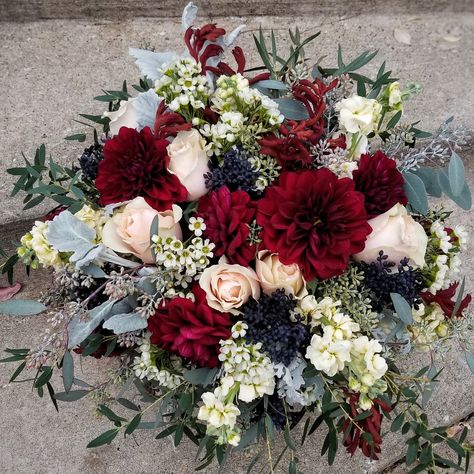 Rustic wax flower texture, unique kangaroo paw stems and blue skimmia berries accent these burgundy dahlias, pink tutu roses and pale yellow stock flowers perfectly. A seasonal bridal bouquet with eucalyptus and dusty miller greens. Maroon And Blue Bouquet, Berry And Blue Wedding, Burgundy And Blue Bouquet, Burgundy And Blue Wedding Flowers, Dusty Blue And Burgundy Wedding Flowers, Burgundy And Navy Bouquet, Dusty Blue And Burgundy Wedding, Burgundy And Blue Wedding, Bridal Bouquet With Eucalyptus