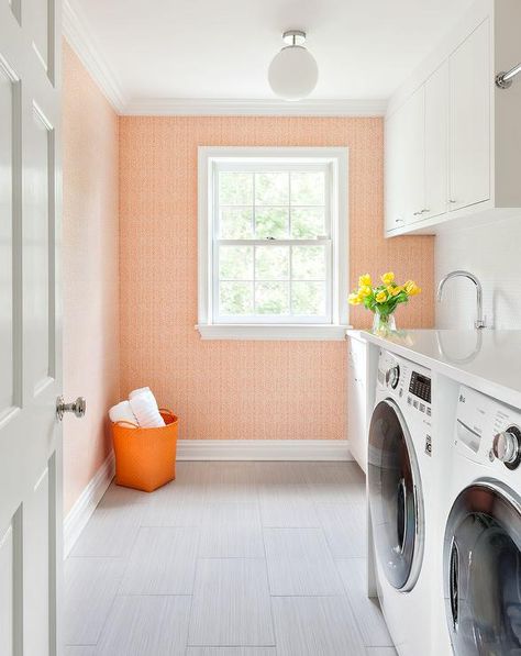 A white glass globe semi flush mount light pendant illuminates a white and orange laundry room boasting a white front loading washer and dryer placed on gray staggered floor tiles beneath a white quartz countertop. Laundry Room Bright, Orange Laundry Room, Wallpaper Laundry Room, Bright Laundry Room, Wallpaper Laundry, Blue Tile Floor, Transitional Laundry Room, Grey Laundry Rooms, Color Durazno