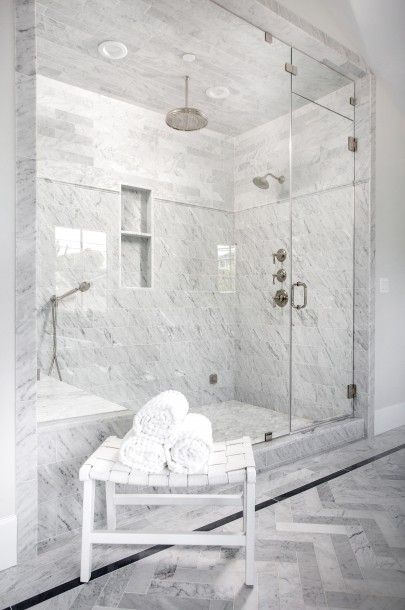 A white leather basketweave bench sits on gray herringbone floor tiles in front of a spacious seamless glass walk in shower finished with a polished nickel circular rain shower head hung from a marble tiled ceiling over a marble floor framed by mixed marble wall tiles framing a tiled niche as the shower is completed with a marble tiled bench and a two polished nickel shower heads. White Tile Shower, White Marble Bathrooms, White Marble Floor, Wall White, Marble Showers, Herringbone Floor, Bathroom Remodel Shower, Marble Bathroom, Shower Remodel