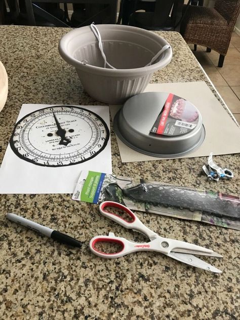 Farmhouse style is really popular, so I thought I'd make a hanging farmhouse kitchen scale to go with my counter scale. It's perfect to hang in the corner and use for holding fruits.  Start it off by tracing a circle using a cake pan. This will be used as the backing for the clock face and to help it stand upright. Next, cut the scale face out. I used the same face that I used for my counter scale. I then glued it to the cardboard. If you can, you can just print the face out on card st… Hanging Scale Decor Ideas, Diy Scale, Farmhouse Kitchen Diy, Wall Vase Decor, Bronze Spray Paint, Farmhouse Fall Wreath, Hanging Scale, Garage Laundry, Kitchen Scales