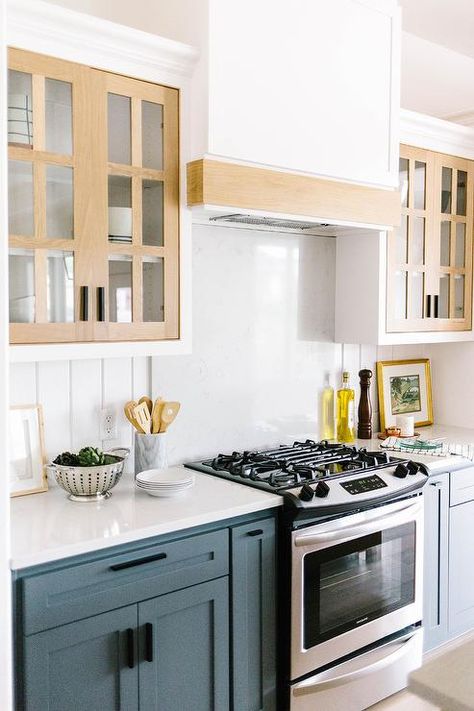 White kitchen cabinets with tan trimmed glass front doors flank a wood trimmed white range hood mounted against a white quartz slab backsplash flanked by vertical tongue and groove trim. Tongue And Groove Backsplash, Mcgregor Homes, Backsplash Designs, Modern Cottage, New Home Builders, Building A New Home, New Home Construction, Wood Trim, White Kitchen Cabinets