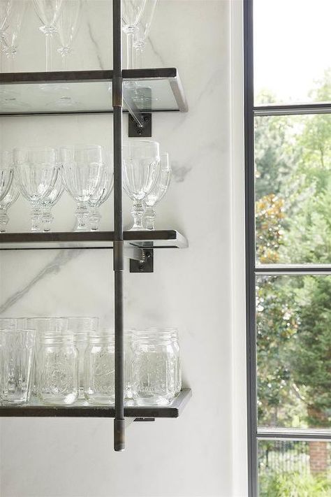 French style iron and glass shelves hang in a kitchen beside a window. Kitchen Shelving Unit, Kitchen Shelf Design, Kitchen Shelving Units, Ikea Glass, Cabinets Ikea, Shelves For Kitchen, Glass Shelves In Bathroom, Glass Shelves Kitchen, Shelves Kitchen