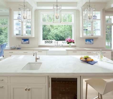 Beautiful white transitional kitchen with a coffered ceiling, a white kitchen island fitted with a glass front fridge and white shaker cabinets topped with honed white marble counters holding a small undermount sink accented with a polished nickel faucet lit by three glass and nickel pendants. White Transitional Kitchen, Glass Kitchen Cabinets, Kitchen Cabinet Shelves, White Shaker Cabinets, White Kitchen Island, Cabinetry Design, Shaker Cabinets, Kitchen Design Decor, Transitional Kitchen