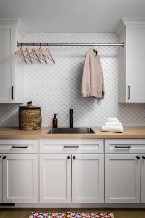 Stylish laundry room design with white cabinetry, wood countertop, modern backsplash tile, and hanging rod for drying clothes. A perfect combination of functionality and contemporary style.Laundry room with white cabinets, wood countertop, backsplash tile, and drying rod.#LaundryRoomDesign #HomeOrganization #InteriorDesign #HomeRenovation #ClarkAndAldinePin Light Gray Laundry Room Cabinets, Laundry Room Ideas White Cabinets, Butcher Block In Laundry Room, Tile In Laundry Room, Laundry Room Tile Backsplash, Laundry Room With White Cabinets, Modern Backsplash Tile, White Cabinets Black Hardware, Laundry Room And Bathroom