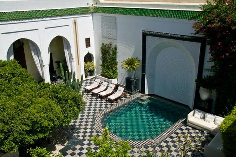 Black-and-white tile sets the scene for this Marrakech, Morocco courtyard. Streamlined lounge chairs and a white sofa sit along the pool, while lush plantings bring a liveliness to the space. Black And White Pool, White Pool, Swimming Pool Landscaping, Book Hotel, Small Swimming Pools, Natural Swimming Pools, Pool Waterfall, Small Pools, Pool Decor