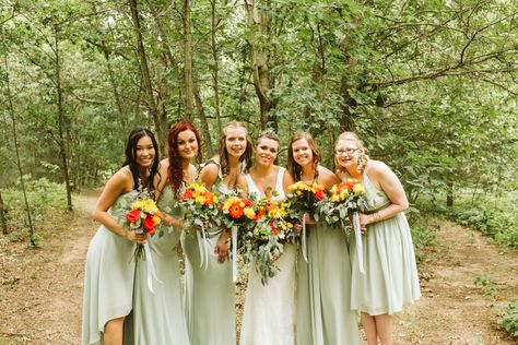 Gorgeous sage green dresses with home made bouquets of real yellow, orange flowers and greenery Mismatched Bridesmaid Dresses Green And Orange, Yellow And Green Wedding Theme Bridesmaid Dresses, Sage Green Bridesmaid Dresses Orange Flowers, Yellow Orange Green Wedding Bridesmaid Dresses, Green Bridesmaid Dresses Orange Flowers, Olive Green Bridesmaid Dress Bright Flowers, Sage Green And Bright Flowers, Green Bridesmaid Orange Flowers, White Flower Boutonniere