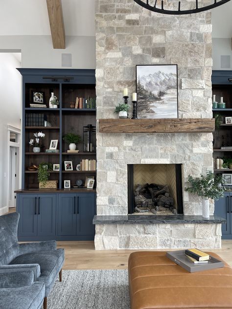 No detail is too small for this living room. The beautiful natural stone blends perfectly with the dark blue paint and walnut accents in the tall display cabinets. And the rough hewn beam is a perfect mantle for family photos and large landscape paintings. Slate Fireplace Wood Mantle, Stone Fireplace Dark Built Ins, Granite Fireplace With Wood Mantle, Modern Farmhouse Fireplace Mantel Stone, Dark Stack Stone Fireplace, Stone Fireplace With Built Ins, Dark Mantle, Grey Stone Fireplace, Walnut Accents