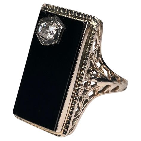 This is an Art Deco 14K white gold, diamond and onyx cocktail ring. It depicts a rectangular black onyx top in white gold bezel setting. The onyx has a reeded gold frame. A round cut diamond on prong setting embellishes one of the corner of the onyx. Each shank of the ring is adorned with a reticulated work made of leaves and hearts. The onyx stone symbolizes courage, power and good fortune. Vintage Onyx Ring, No Ordinary Girl, Gold Pinky Ring, The Bling Ring, Vintage Art Deco Rings, Black Onyx Ring, Celtic Jewelry, Deco Jewelry, Filigree Ring