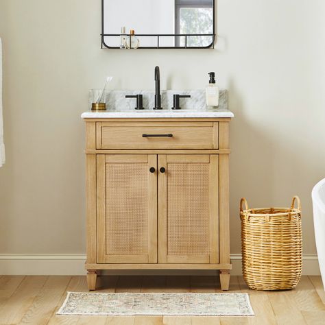 Infuse coastal chic into your bathroom with the allen + roth Wallister 30-inch bathroom vanity. Wallister pairs classic caning with a natural oak wood finish to deliver a beautiful centerpiece to your bathroom. The cabinet features a solid wood frame and 2 reversible soft-closing doors, so it’s easy to change the look from coastal to traditional. A tilt-down drawer, adjustable shelf, and power outlet provide abundant storage and convenience. The Natural laminated Carrara white marble top comes with a pre-installed rectangular sink and is pre-drilled for an 8-in widespread faucet. This smaller vanity is perfect for a guest or powder room, but Wallister is also available in a larger 48-in profile for bigger bathrooms. allen + roth Wallister 30-in Wood Undermount Single Sink Bathroom Vanity w Undermount Bathroom Sink Vanity, 35 Inch Bathroom Vanity, Small Simple Bathroom Remodel, 30 Inch Bathroom Vanity Wood, Small Bath Vanity Ideas, Small Bathroom Vanity With Storage, Rattan Vanity Bathroom, Wooden Sink Unit Bathroom, Small Bathroom Inspiration Decor