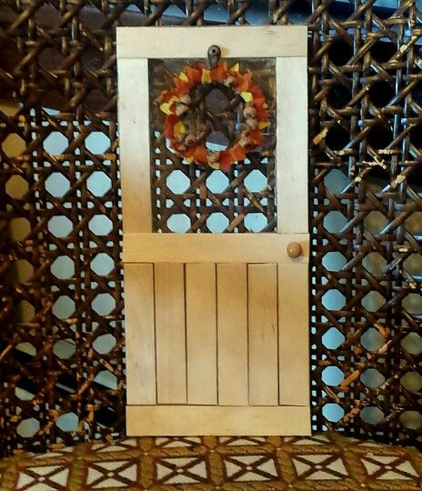 Barbie popsicle stick door with cardboard. Plastic packaging window. Wreath is made of a fake flower, wire ring, and tiny acorns. Popsicle Stick Door, Popsicle Stick Wreath Front Doors, Dollhouse Door Tutorial, Popsicle Stick Fairy Door, Dollhouse Door Template, Door Miniature, Lolly Stick Craft, Easy Popsicles, Popsicle Stick Crafts House