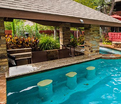 Swim-Up Bars are a great way to bring the fun of having a cocktail or food served to you in the pool because if you don’t have to get out why would you? These areas feature built-in bar stools made of stone, tile or precast finishes and a bar that can be adorned in glass tile or beads. The options are endless. Pool With Bar Stools, Outdoor Pool Showers, Pool With A Bar, Swimup Bar Swimming Pools, Swim Up Bar Pool Backyards, Swim Up Pool Bar Ideas, Pool Bar Stools, Poolside Bar Ideas, Swim Up Bar Pool