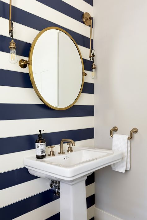 Statement wall with the gold fixtures and gold finished mirror gives off an elegant lakehouse feel. Love the simplicity combined with a fun pattern. Striped Bathroom Walls, Blue Vanity Bathroom, Nautical Interior Design, Navy Bathroom, Nautical Interior, Blue Accent Walls, Nautical Bathroom Decor, Blue Vanity, Coastal House