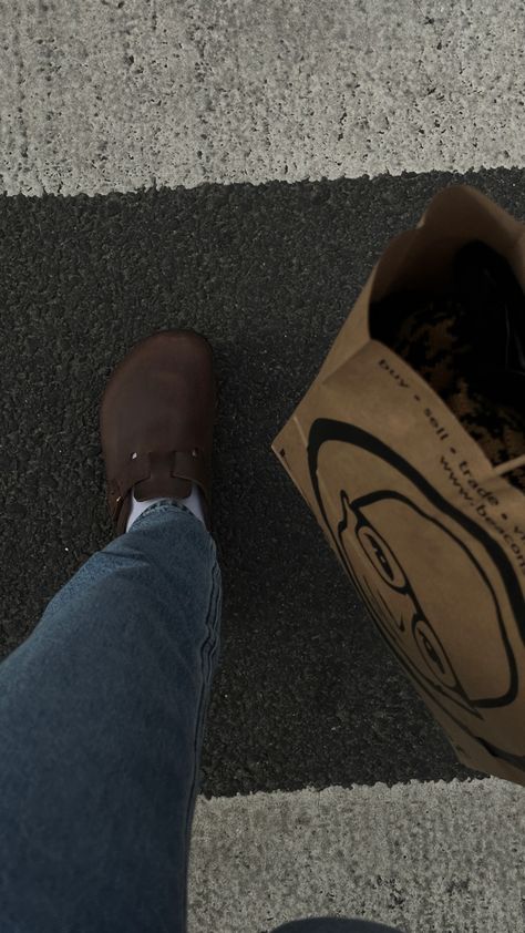 bird’s eye view shot of feet walking on a crosswalk. maia is wearing dark brown oiled leather birkenstocks with white socks and light-wash levi’s jeans. a brown paper bag with clothes inside is on the side of the image. Brown Birks Outfit, Black Leather Boston Birkenstocks Outfit, Brown Leather Birkenstocks Outfit, Leather Boston Clogs Outfit, Oiled Leather Birkenstocks Outfit, Dark Brown Boston Clogs Outfit, Leather Boston Birkenstocks, Mocha Boston Birkenstock Outfit, Brown Birkenstock Outfit